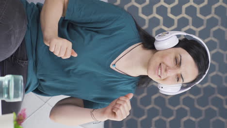 Vertical-video-of-Woman-looking-out-the-window-and-listening-to-music-with-headphones.